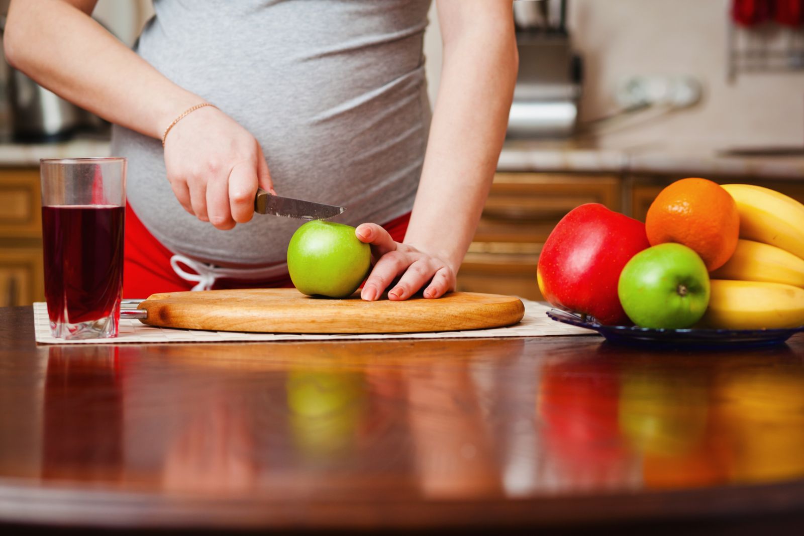 Беременная женщина режет фрукты