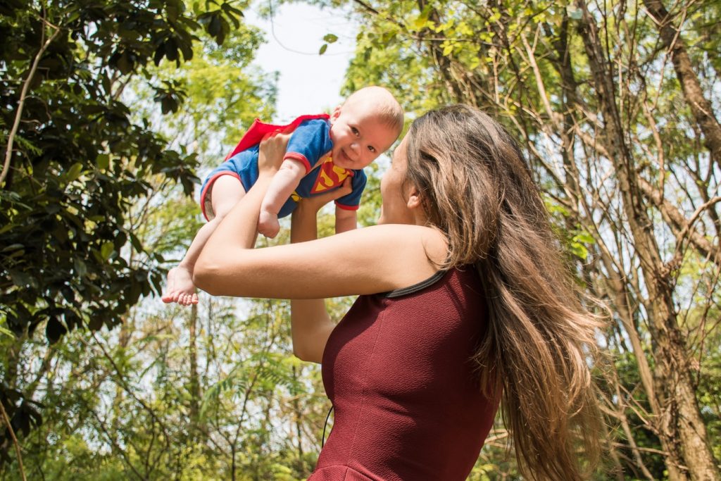 Мама держит младенца в костюме супергероя